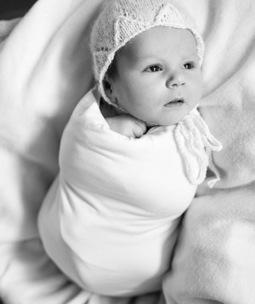 Portrait noir et blanc d'un nouveau-né emmailloté en blanc bonnet blanc, photographie artistique de nouveau-né Houilles