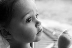 Portrait noir et blanc d'une petite fille qui regarde par la fenêtre, homestudio Houilles, photographe enfants Houilles