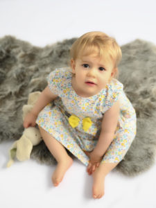 Petite fille robe fleurie assise sur fourrure Photographe bébé Houilles Photographe Houilles