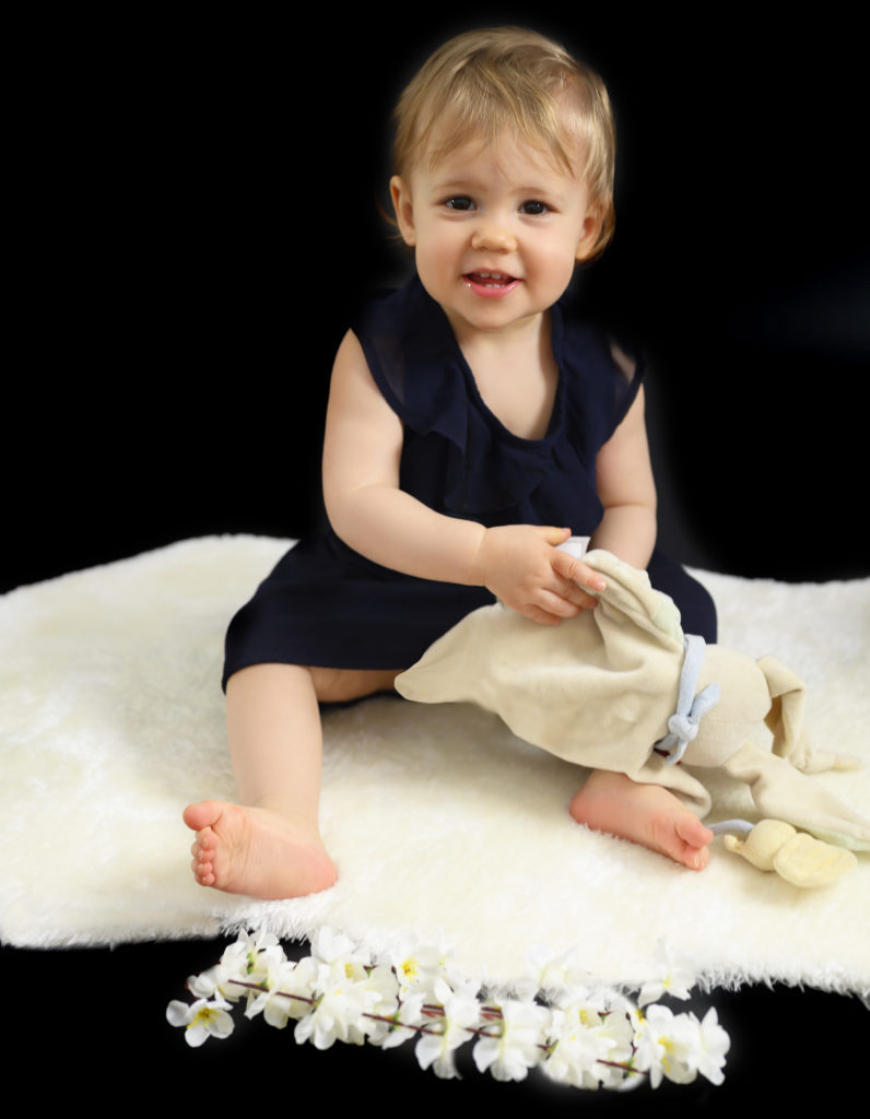 petite fille assise sur une fourrure blanche qui fait un grand sourire photographe bébé Houilles photographe Houilles