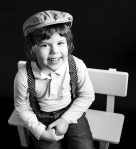 Portrait noir et blanc d'un petit garçon avec un béret et des bretelles assis sur un banc Photographe enfant Houilles Photographe enfants Houilles Photographe Houilles