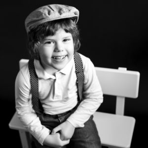 Portrait noir et blanc d'un petit garçon avec une casquette rétro et des bretelles Photographe enfant Houilles Photographe enfant Houilles Photographe Houilles