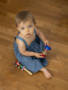 petite fille aux yeux bleus en robe bleue assise sur un parquet photographe bébé Houilles photographe Houilles