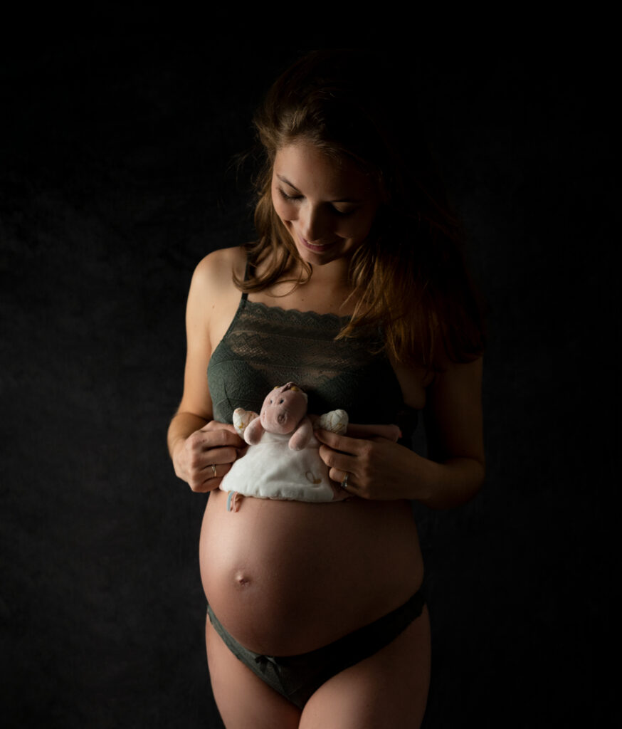 Femme enceinte tenant le doudou de son futur bébé sur son ventre photographe grossesse Houilles photographe grossesse la Défense photographe grossesse Yvelines