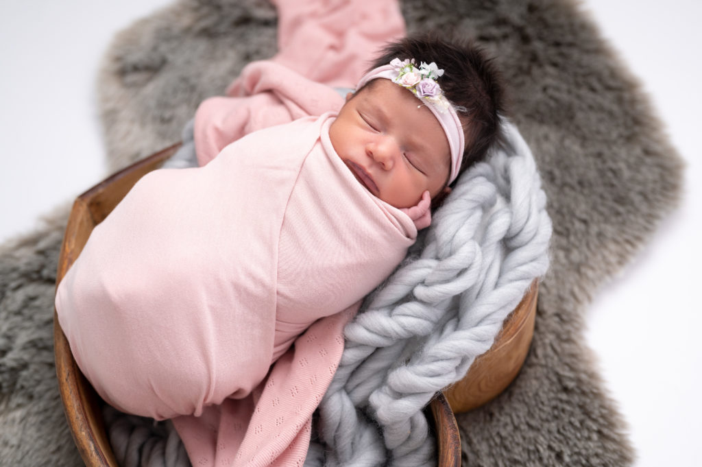 nouvelle née emmaillotée de rose headband rose endormie dans coeur en bois sur tresse en laine grise photographe naissance nouveau-né Houilles Yvelines la Défense