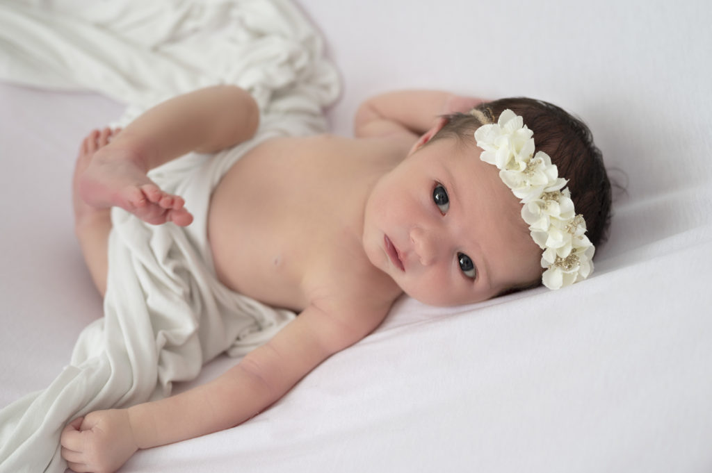 bébé fille headband blanc allongée sur le dos regard objectif
photographe naissance Houilles