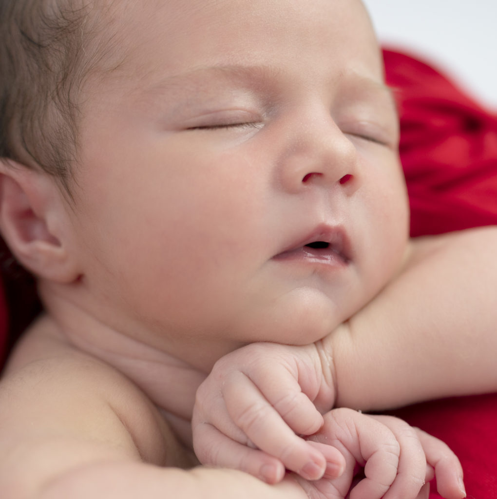 nouveau-né endormi dans un panier avec wrap rouge photographe naissance houilles yvelines