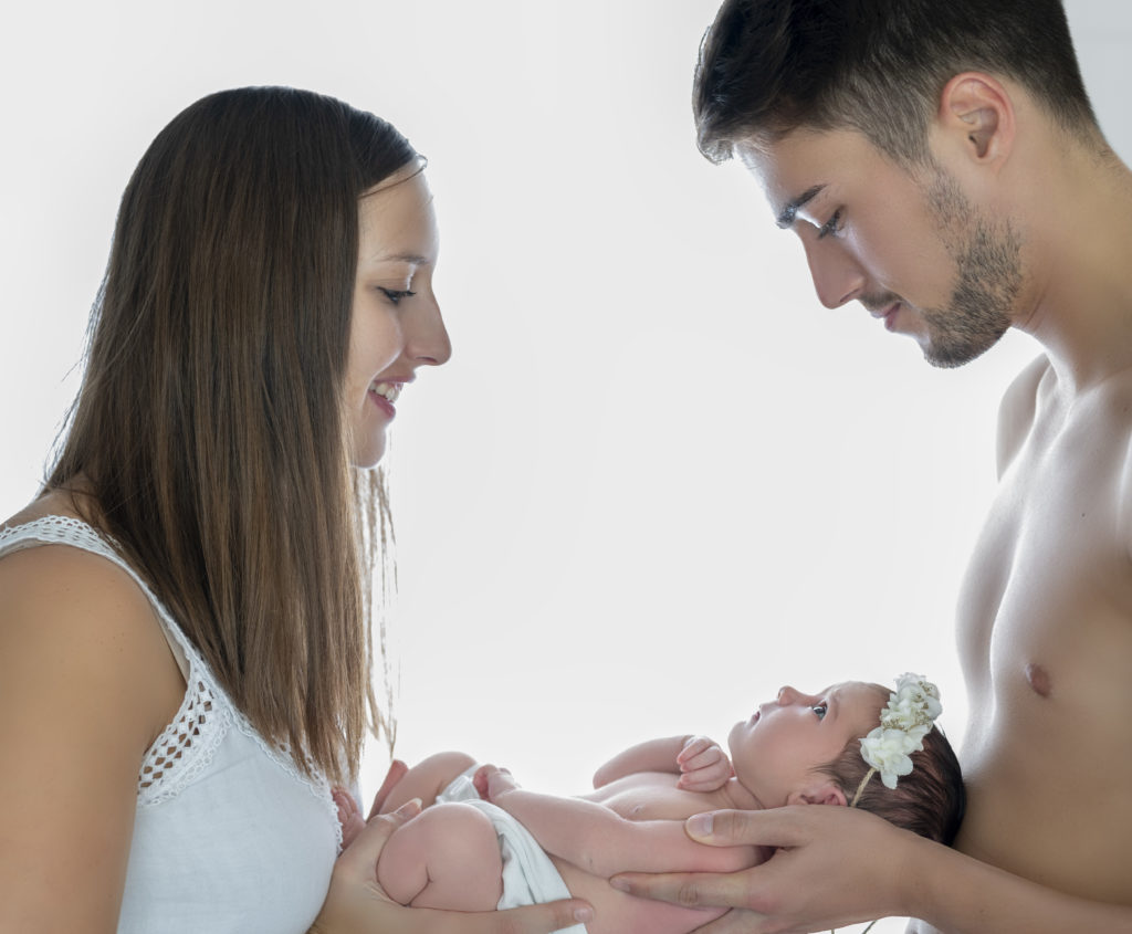 Jeunes parents tenant leur nouvelle-née dans les bras à contrejour photographe naissance famille Houilles Yvelines