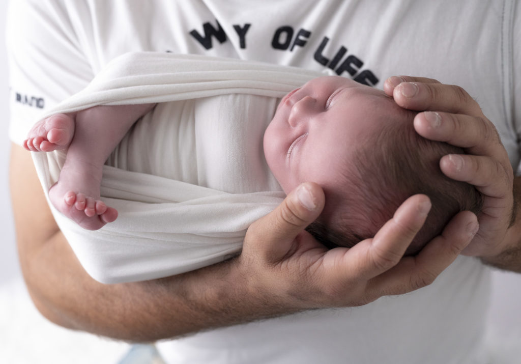 nouveau-né endormie dans les mains de son papa photographe naissance nouveau-né houilles yvelines la défense