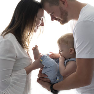 jeunes parents en contrejour tenant leur bébé de 8 mois dans leurs bras photographe bébé Houilles Yvelines la Défense photographe famille Houilles Yvelines la Défense