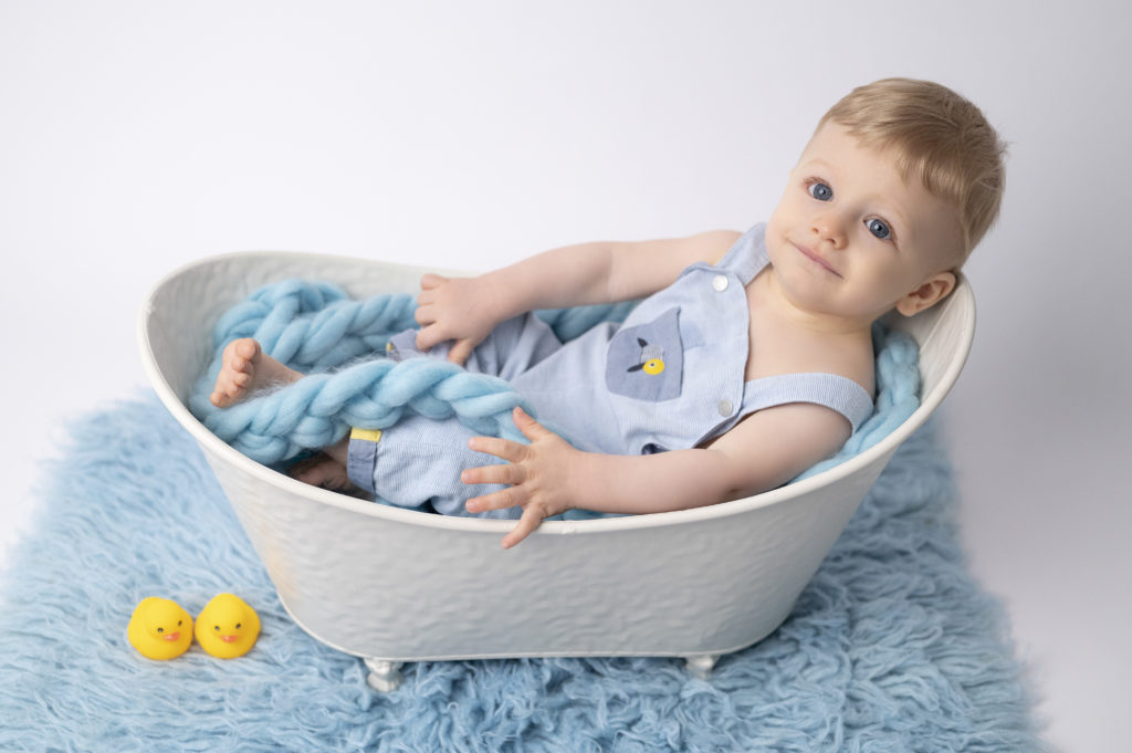 Bébé de huit mois allongé dans une mini baignoire avec petits canards jaunes photographe bébé famille Houilles Yvelines la Défense