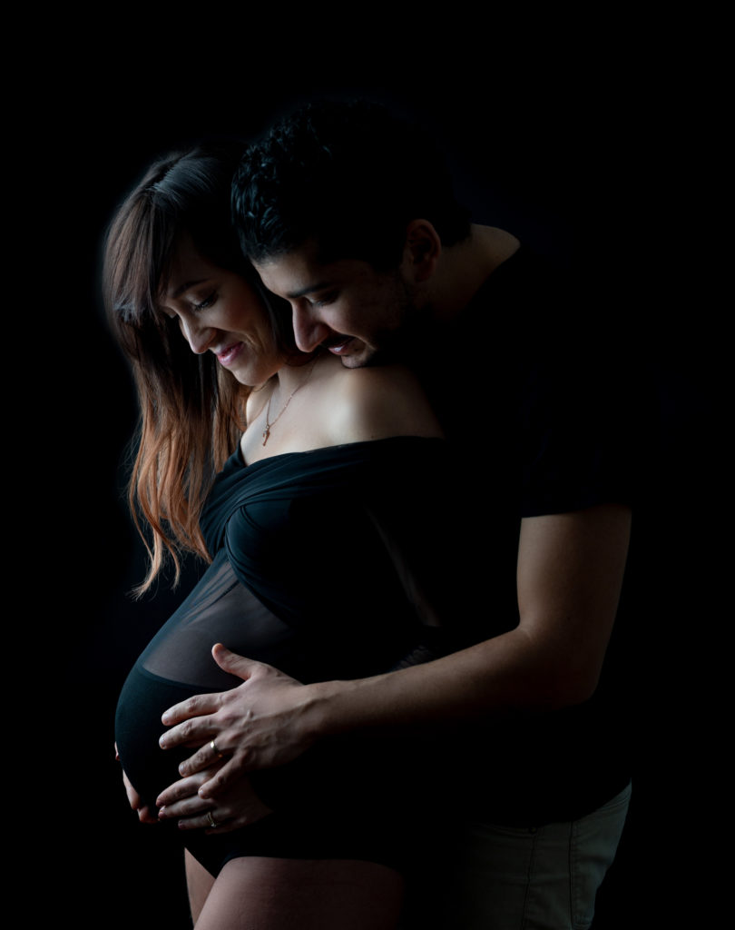 femme enceinte et son mari qui la tient contre lui la main sur son ventre photographe grossesse femme enceinte Houilles Yvelines la Défense