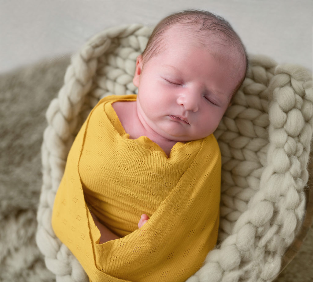 nouveau-né emmailloté de jaune moutarde endormi dans terrine sur tresse en laine grise photographe naissance nouveau-né Houilles Yvelines la Défense