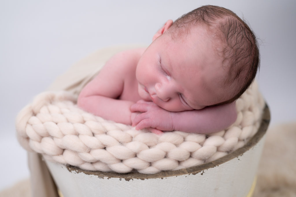 nouveau-né endormi dans un seau en bois sur pose bébé en laine crème photographe naissance nouveau-né Houilles Yvelines la Défense