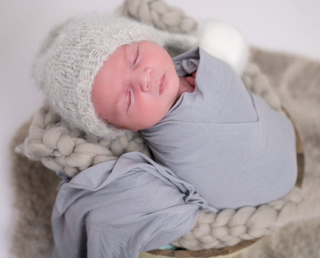 nouveau-né emmailloté de gris bonnet d'elfe endormi dans terrine ronde sur tresse en laine grise photographe naissance nouveau-né Houilles Yvelines la Défense