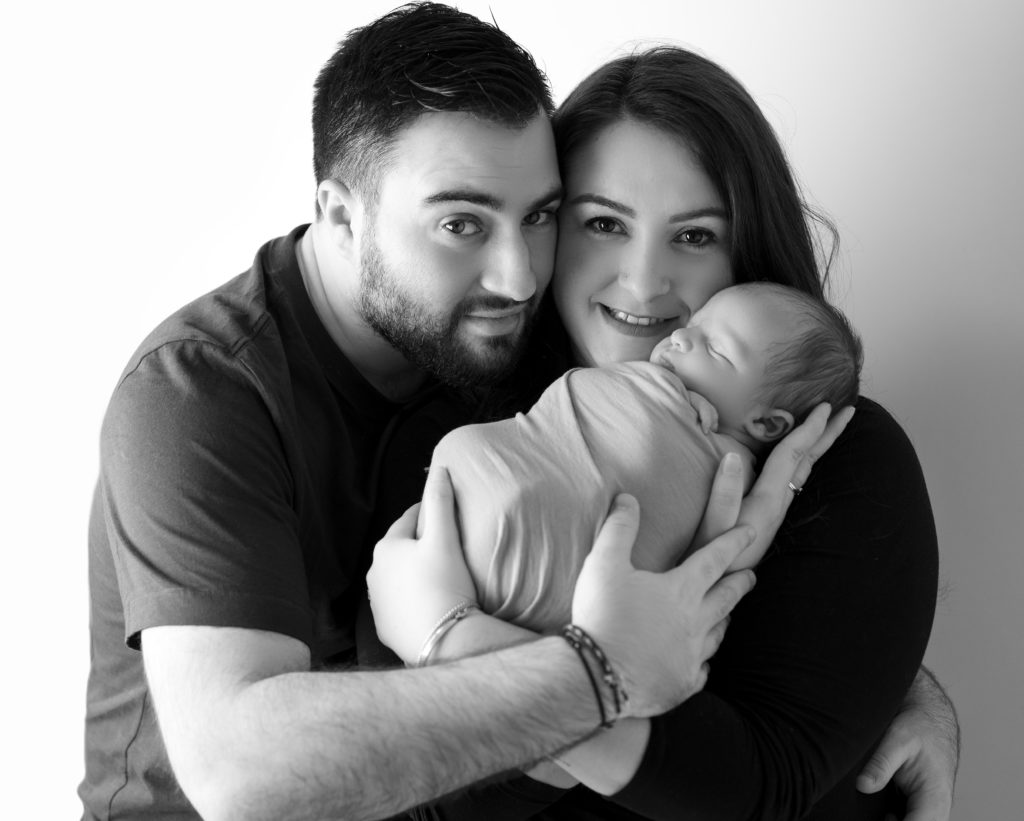 photo en noir et blanc d'un nouveau-né endormi dans les bras de ses parents photographe naissance nouveau-né bébé Houilles Yvelines la Défense