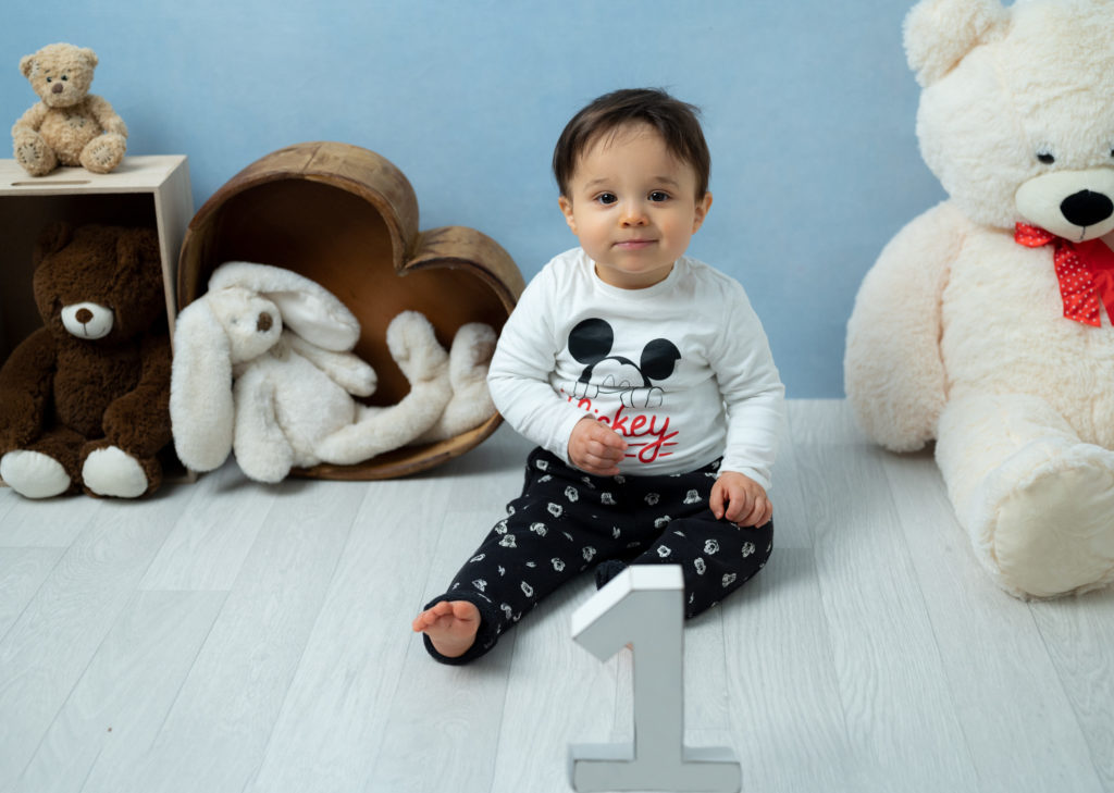 bébé de un an assis sur fond bleu avec peluches et nounours photographe grand bébé Houilles Yvelines la Défense
