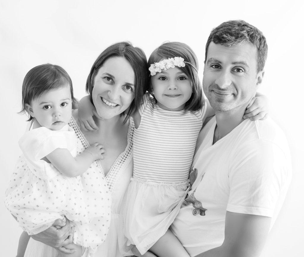 Portrait noir et blanc d'une famille avec les parents tenant leurs petites filles dans les bras photographe famille Houilles Yvelines la Défense