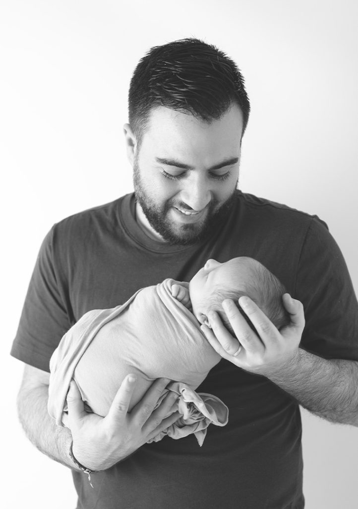 jeune papa tenant son nouveau-né dans les bras. Photographe naissance nouveau-né Houilles Yvelines la Défense