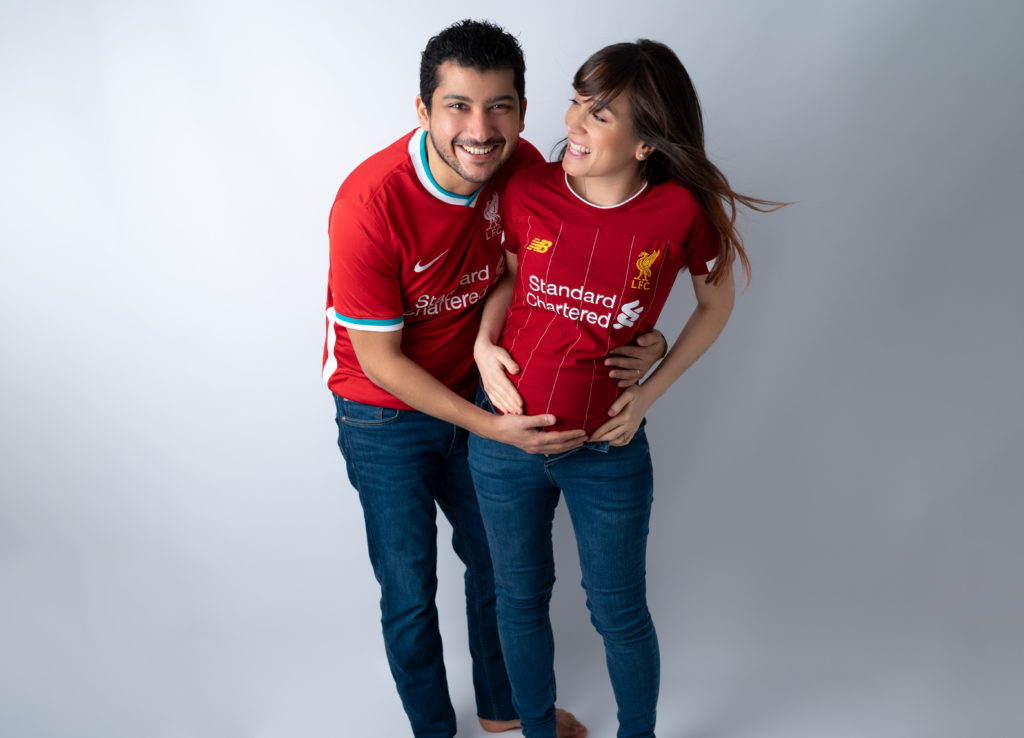Couple femme enceinte en maillot de Liverpool mains sur le ventre de la femme enceinte photographe grossesse maternité Houilles Yvelines la Défense