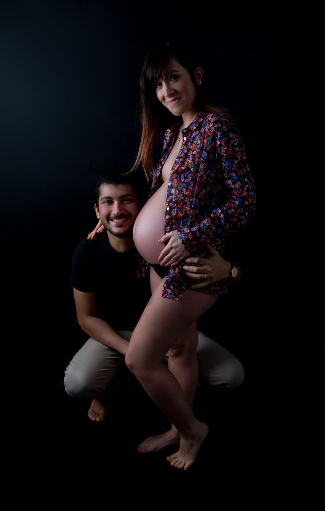 photo de couple femme enceinte chemise ouverte sur fond noir mains sur le ventre de la femme enceinte photographe grossesse maternité Houilles Yvelines la Défense