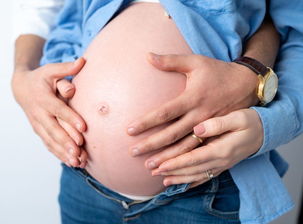 Gros plan sur les mains d'un couple sur le ventre de la femme enceinte mains sur le ventre de la femme enceinte photographe grossesse maternité Houilles Yvelines la Défense