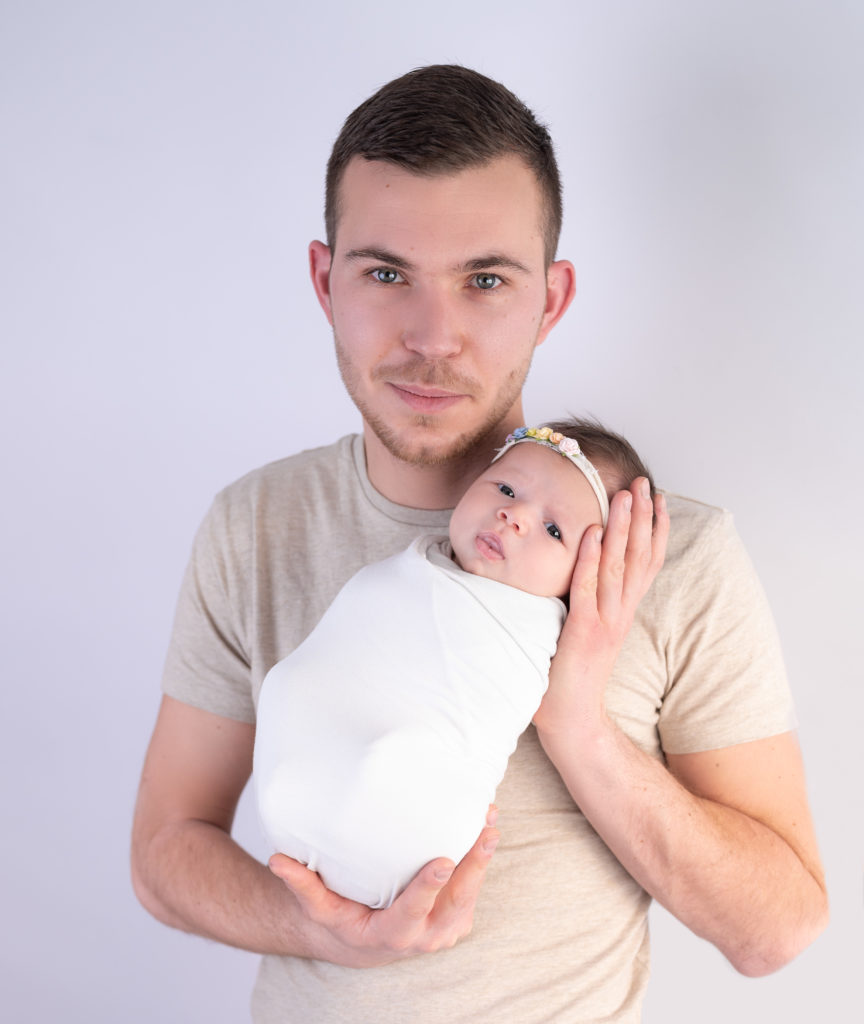 Jeune papa tenant son nouveau-né emmailloté dans les bras photographe naissance nouveau-né Houilles Yvelines la Défense