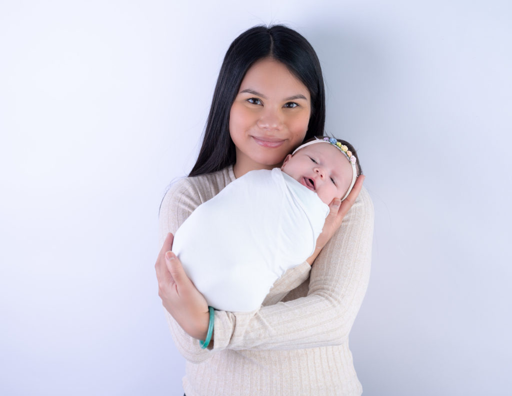 Jeune maman tenant son nouveau-né emmailloté dans les bras photographe naissance nouveau-né Houilles Yvelines la Défense