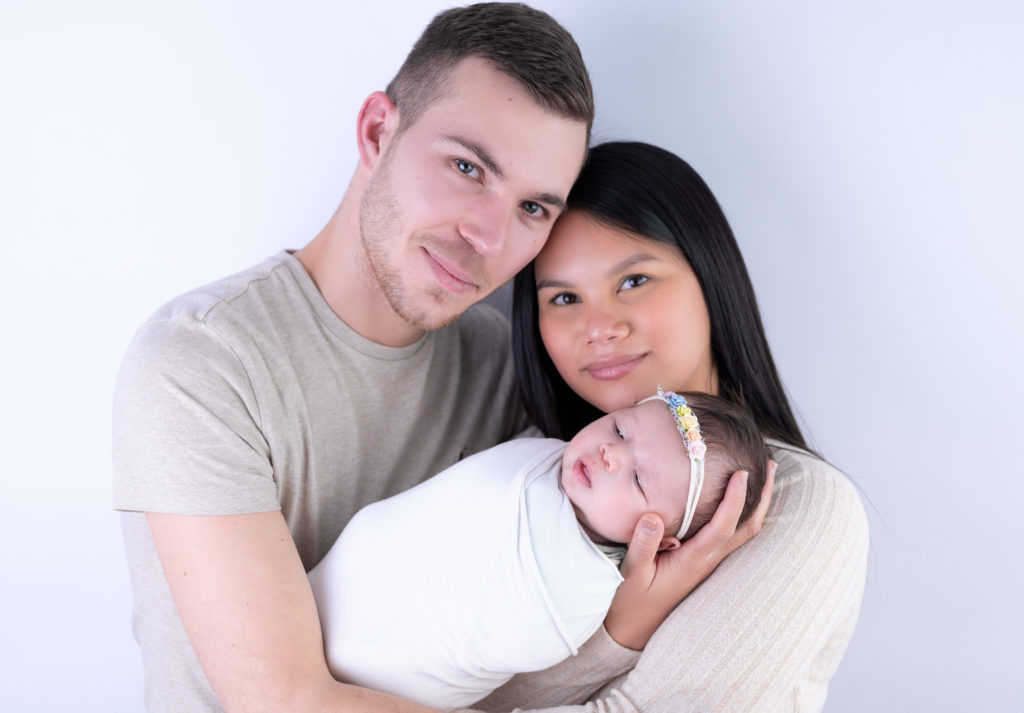 Jeunes parents tenant leur nouveau-né emmailloté dans les bras photographe naissance nouveau-né Houilles Yvelines la Défense