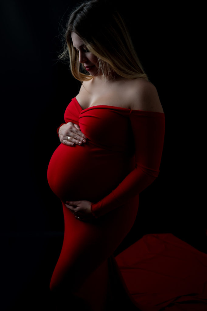 femme enceinte en clair obscur robe rouge sur fond noir photographe grossesse maternité femme enceinte Houilles Yvelines la Défense