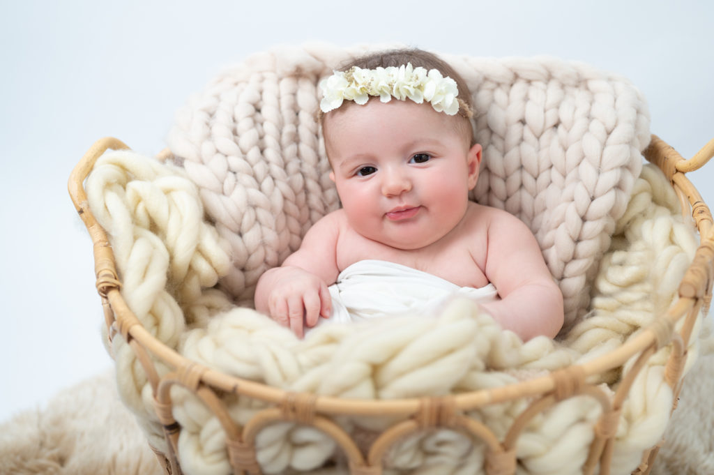 bébé de deux mois installée dans un panier dans des tons blancs tresse en laine et pose bébé en laine écrus photographe bébé Houilles Yvelines la Défense