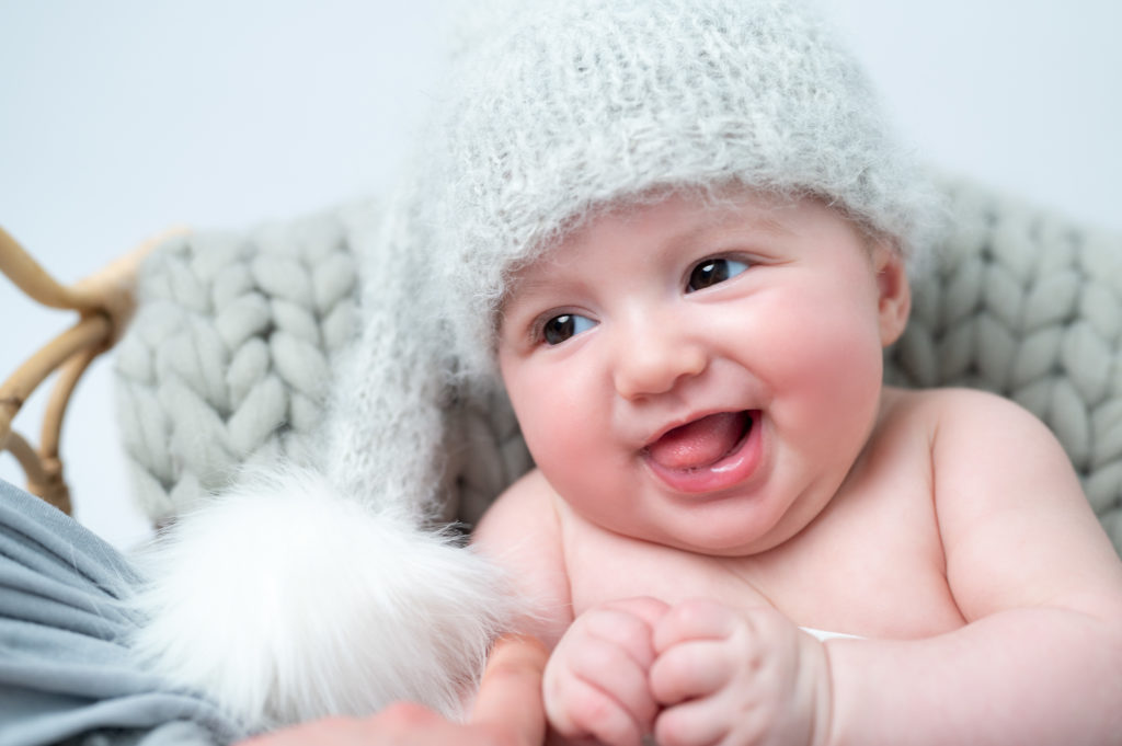 bébé de deux mois bonnet d'elfe gris dans un panier sur pose bébé en laine gris sourit photographe bébé Houilles Yvelines la Défense