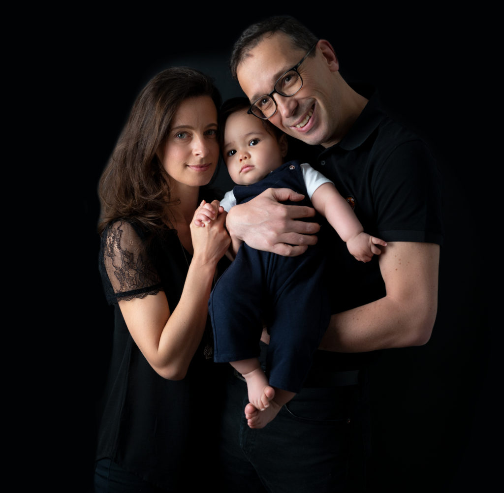 parents et leur bébé de huit mois sur fond noir photographe bébé famille Houilles Yvelines la Défense