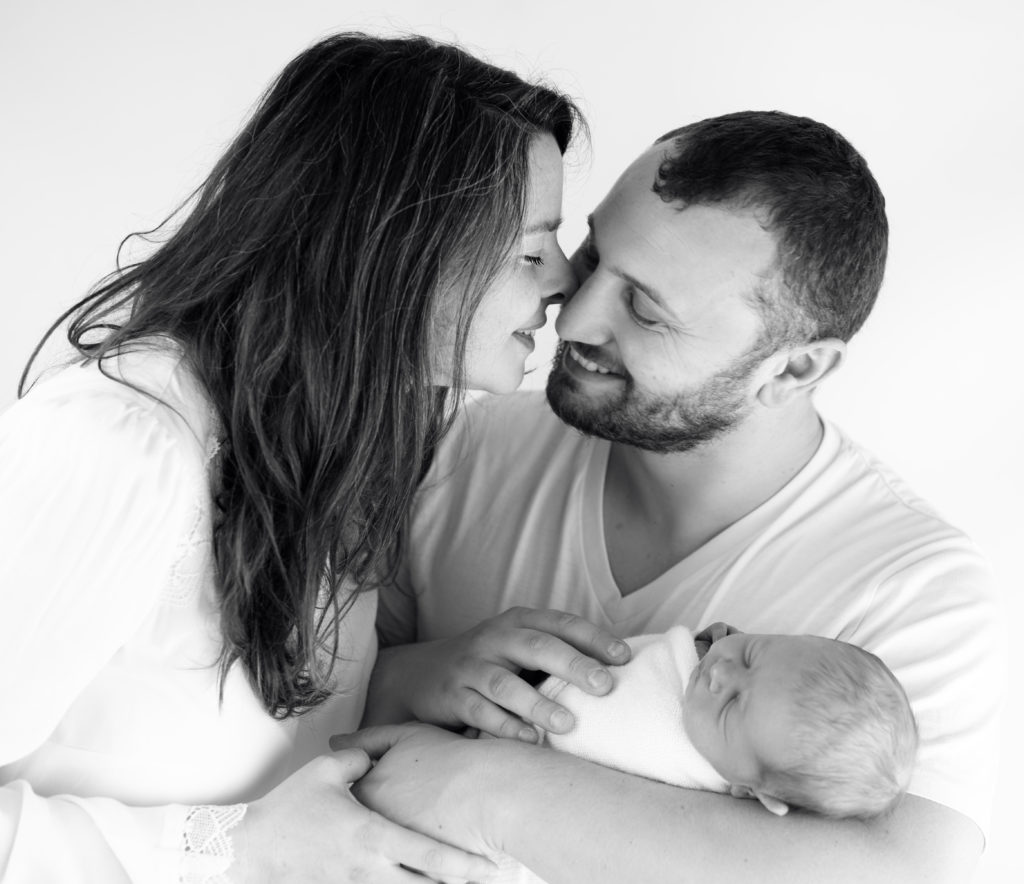 couple de jeunes parents et leur nouveau-né endormi dans leurs bras photographe famille Houilles Yvelines la Défense