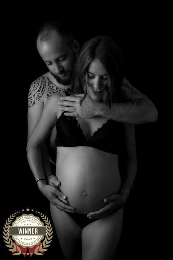 Couple de futurs parents sur fond noir photo noir et blanc photographe grossesse femme enceinte Houilles Yvelines la Défense