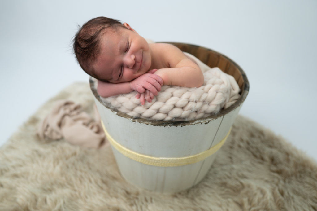 Nouveau-né endormi dans un seau en bois sourire photographe naissance nouveau-né Houilles Yvelines la Défense