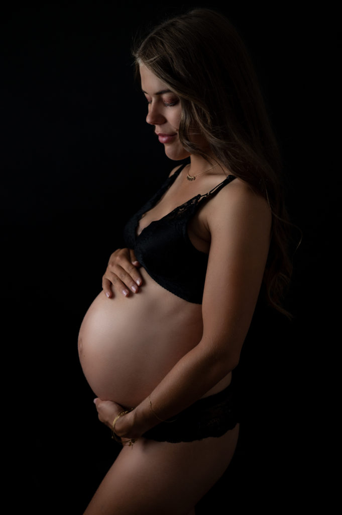 Femme enceinte dessous noirs sur fond noir regard ventre photographe femme enceinte maternité Houilles Yvelines la Défense