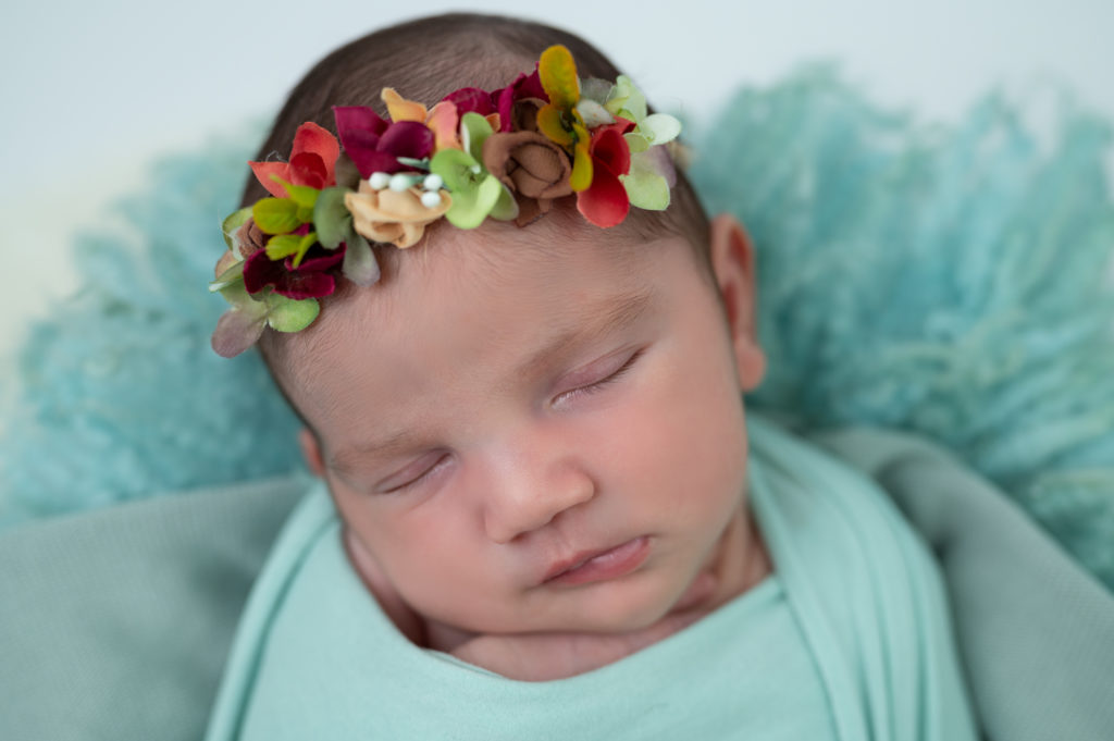 nouvelle-née halo vert et rouge emmaillotée de vert endormie dans une terrine ronde photographe naissance nouveau-né Houilles Yvelines la Défense