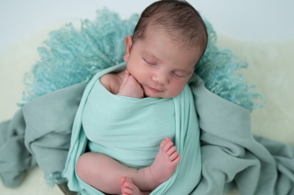 nouvelle-née emmaillotée de vert endormie dans une terrine ronde photographe naissance nouveau-né Houilles Yvelines la Défense