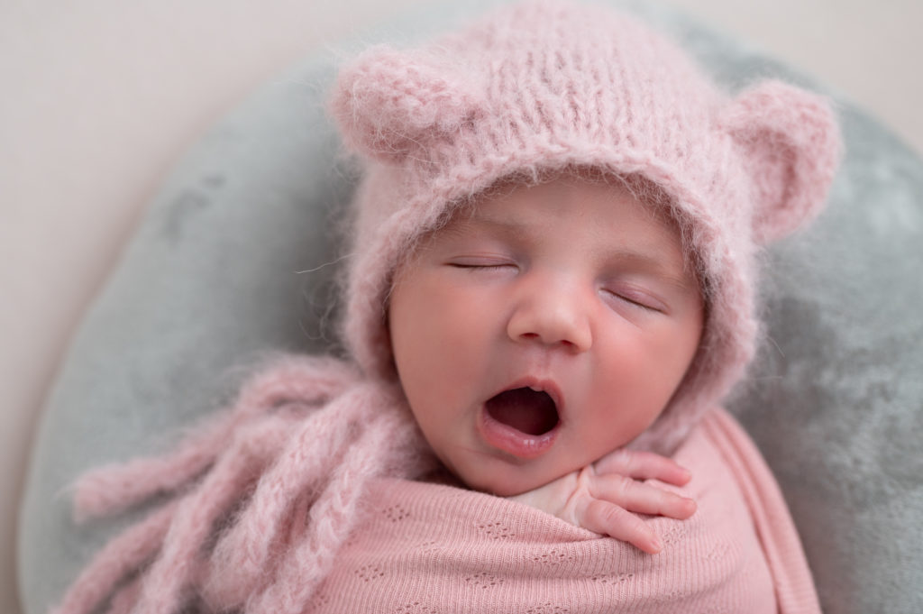 nouveau-né emmaillotée de rose sur lune grise en velours bonnet rose à oreilles d'ours baille photographe naissance nouveau-né Houilles Yvelines la Défense