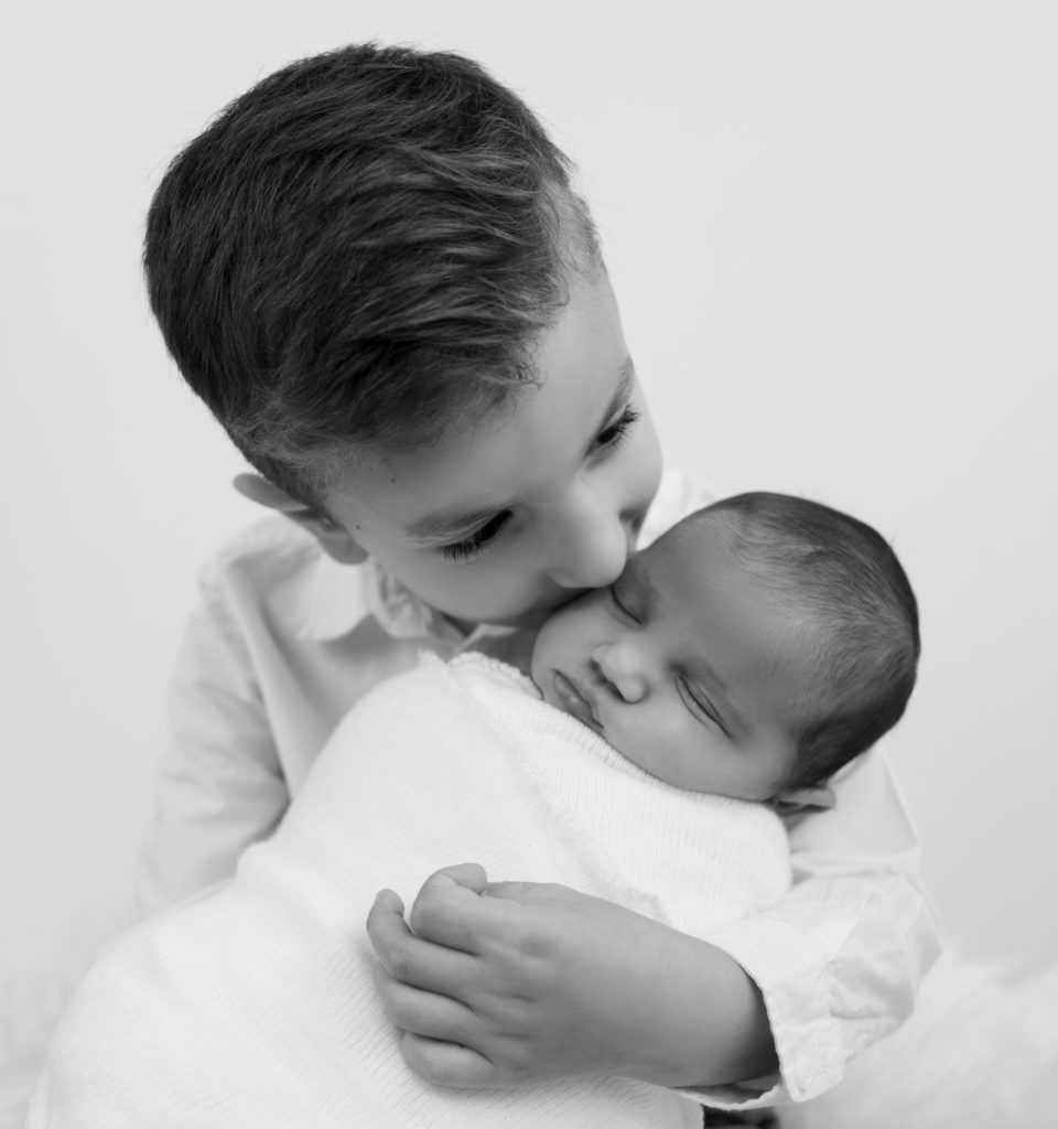 petit garçon tenant sa soeur nouvelle-née dans ses bras photographe naissance bébé famille Houilles Yvelines la Défense