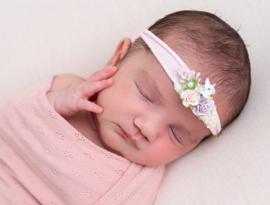 nouvelle-née headband fleuri emmaillotée de rose endormie sur posing bag rose photographe naissance nouveau-né Houilles YVelines la Défense
