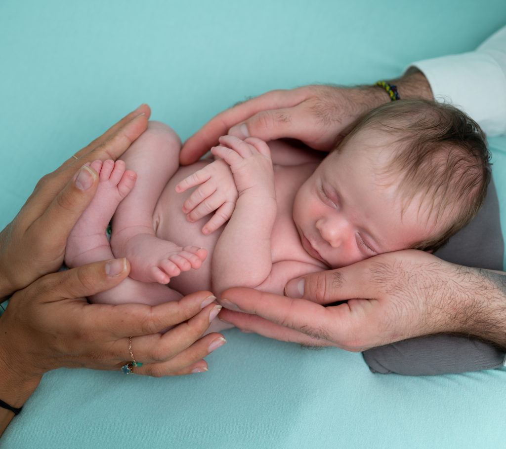 nouveau-né endormi dans les mains de ses parents photographe naissance nouveau-né Houilles Yvelines la Défense
