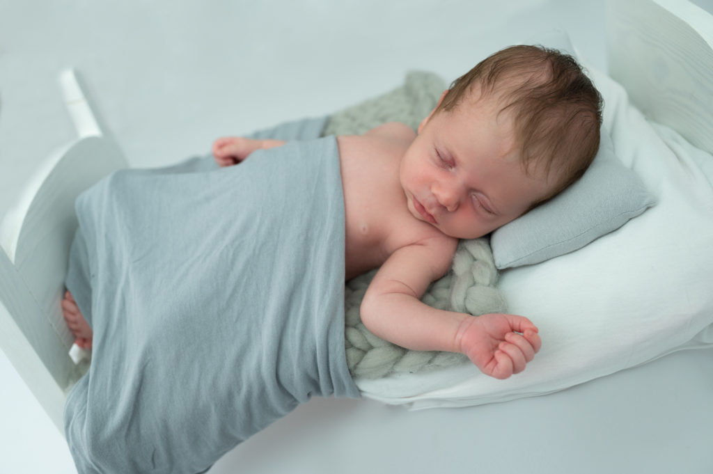 nouveau-né endormi dans un petit lit en bois blanc photographe naissance nouveau-né Houilles Yvelines la Défense