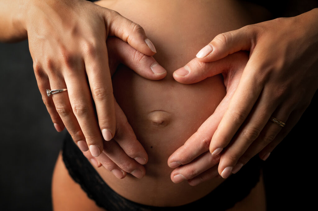 mains de futurs parents entourant le ventre rond d'une femme enceinte photographe grossesse Houilles photographe grossesse la Défense photographe grossesse Versailles photographe grossesse Yvelines 