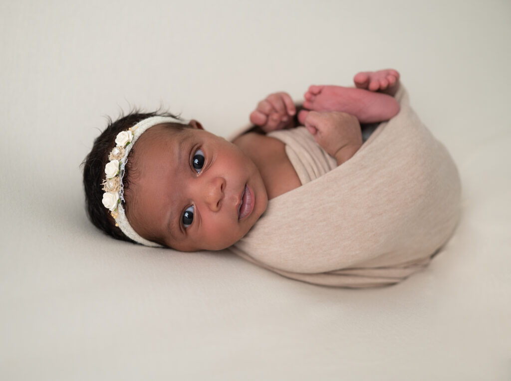 bébé emmaillotée de beige regard objectif photographe naissance Houilles photographe famille Houilles