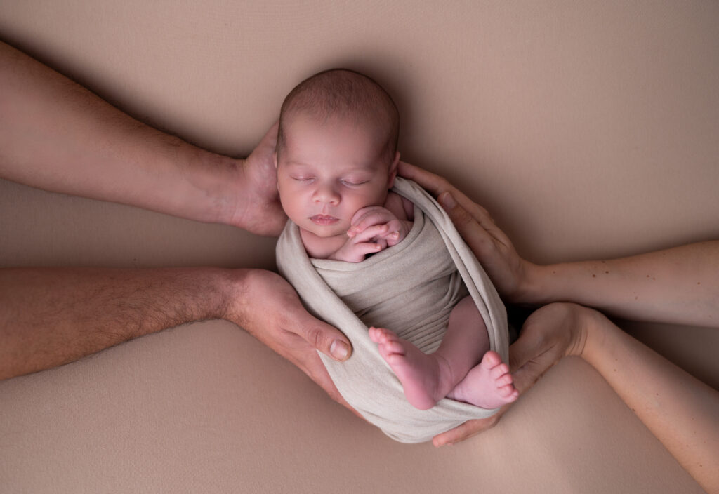 nouveau-né endormi dans les mains de ses parents photographe naissance Houilles photographe naissance la Défense photographe Houilles photographe Versailles photographe Rueil-Malmaison photographe Chatou photographe Yvelines photographe Ile-de-France