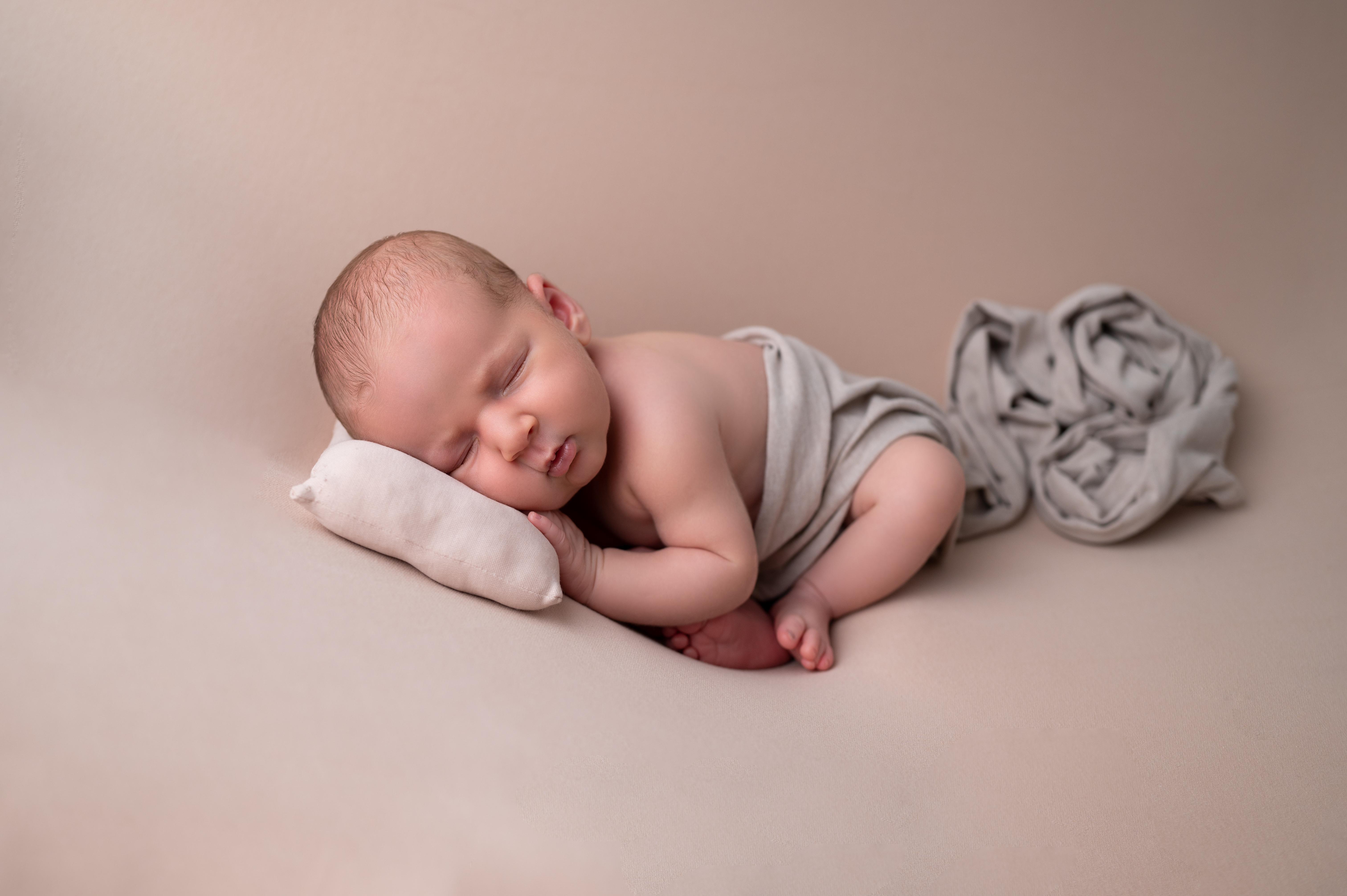 nouveau-né endormi sur fond beige uni photographe naissance Houilles photographe naissance la Défense photographe Houilles photographe Versailles photographe Rueil-Malmaison photographe Chatou photographe Yvelines photographe Ile-de-France