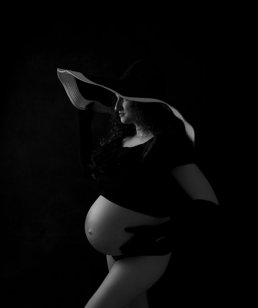 Femme enceinte longs gants chapeau large sur fond noir photographe grossesse Houilles photographe grossesse Yvelines photographe grossesse Versailles