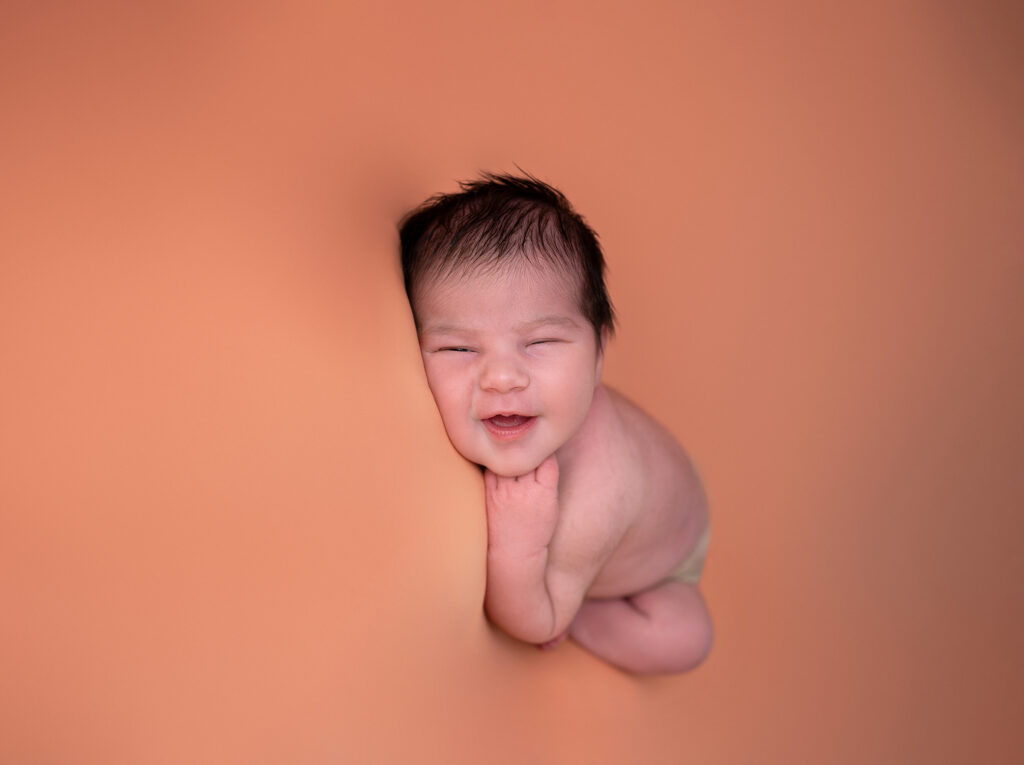 Bébé endormi sur fond orange sourire photographe nouveau-né Houilles photographe naissance Houilles photographe naissance carrières-sur-seine photographe naissance sartrouville photographe naissance chatou photographe naissance yvelines photographe naissance versailles photographe naissance ile-de-france photographe naissance paris